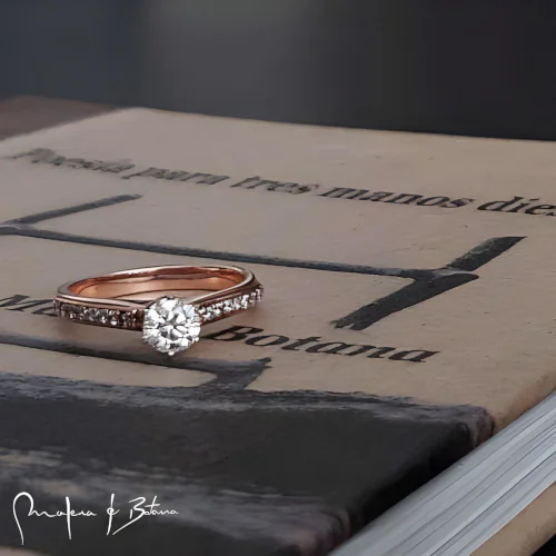 Anillo de compromiso en oro rosa con piedra central solitario y banda con pavé de piedras