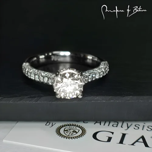 Anillo de compromiso en platino con piedra central y pavé de piedras, destacando su elegancia y brillo.