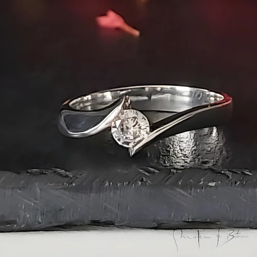 Anillo de compromiso en plata con una piedra central y diseño fluido, destacando su elegancia y originalidad.