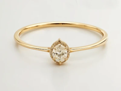 Anillo de promesa en oro 18k con diamante en forma oval y halo de piedras, diseño delicado y elegante.