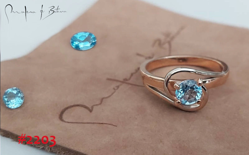 Anillo de oro rosa con una piedra redonda de topacio azul. Número de artículo: #2203.