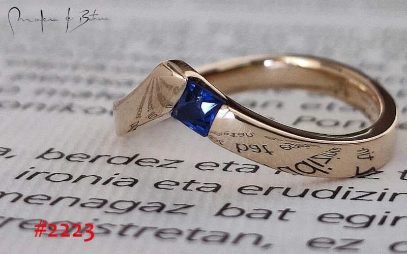 Anillo de oro amarillo con zafiro azul y una inscripción grabada en la banda, modelo #2223 de Malena de Botana.