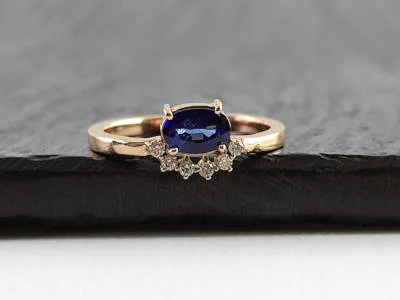 Anillo de oro rosa con un zafiro azul ovalado central y una pavé de diamantes, modelo #2018 de Malena de Botana.