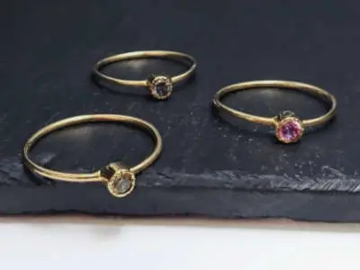 Tres anillos de oro con pequeñas piedras de colores (gris, rosa y morado). Número de artículo: #2202.
