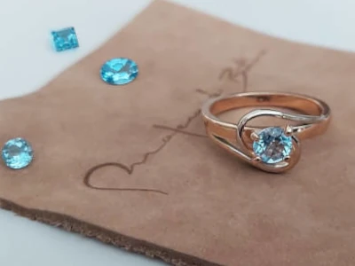 Anillo de oro rosa con una piedra redonda de topacio azul. Número de artículo: #2203.