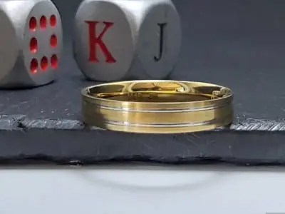 Primer plano de una alianza de oro de dos tonos con detalles acanalados, modelo #2214 de Malena de Botana.