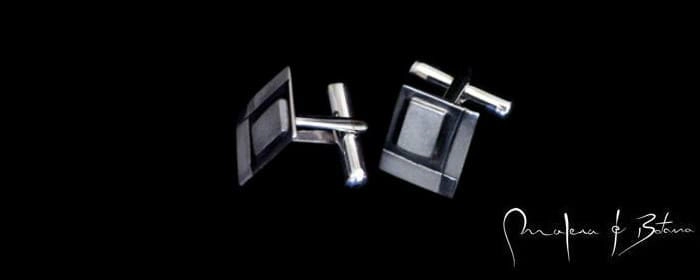 Gemelos de plata con diseño geométrico de la marca [Nombre de la marca, si aplica, o Artesanía en Plata si no se especifica]. La imagen ilustra la idea de Estilo Eres Tú, representando cómo los accesorios pueden reflejar la personalidad y el estilo individual. El fondo negro resalta la elegancia y los detalles de las piezas.
