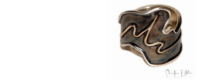 anillo artesanal con diseño ondulante en plata patinada, mostrando formas orgánicas y fluidas características del trabajo manual, firmado por el artista joyero
