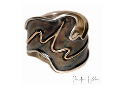 anillo artesanal con diseño ondulante en plata patinada, mostrando formas orgánicas y fluidas características del trabajo manual, firmado por el artista joyero