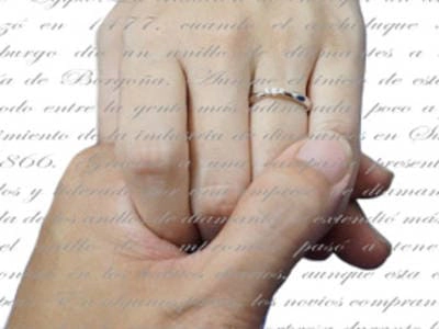 Imagen de una mano femenina con un anillo de compromiso solitario, superpuesta sobre un texto manuscrito antiguo, ilustrando la fusión entre tradición y decisión personal en la selección de anillos de compromiso