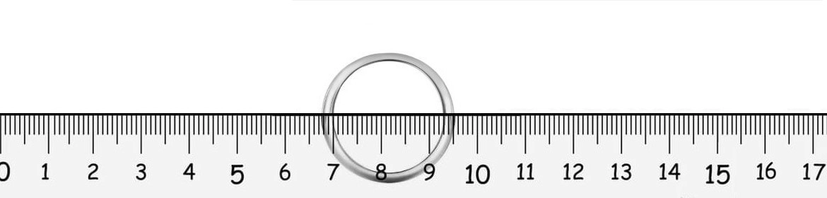 Medición precisa de un anillo de compromiso: Determinando la talla exacta Anillo de compromiso solitario sobre una regla de joyería, mostrando la medición del diámetro interno entre las marcas de 5 y 6 centímetros, ilustrando el método para determinar la talla del anillo