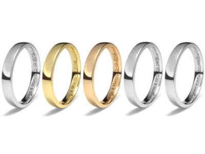 Cinco anillos de boda lisos alineados horizontalmente. De izquierda a derecha: dos anillos de platino o paladio, uno de oro amarillo, uno de oro rosa, y dos más de platino o paladio. Todos los anillos tienen un acabado pulido y brillante, mostrando diferentes tonos metálicos.