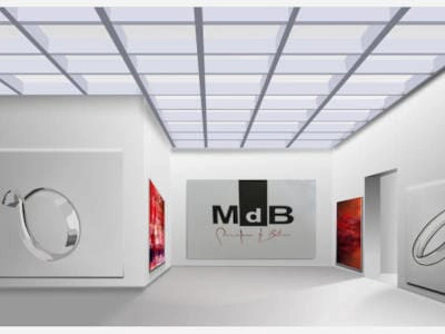 Interior de una galería de arte blanca y moderna con techo de paneles cuadrados y luz natural. Varias obras de arte, incluyendo pinturas abstractas rojas y esculturas plateadas con forma de anillo, están colgadas en las paredes. Un gran cartel con el logotipo MdB y la inscripción en rojo y negro es el punto focal de la sala. La galería parece espaciosa y minimalista, con un enfoque en las obras de arte expuestas.