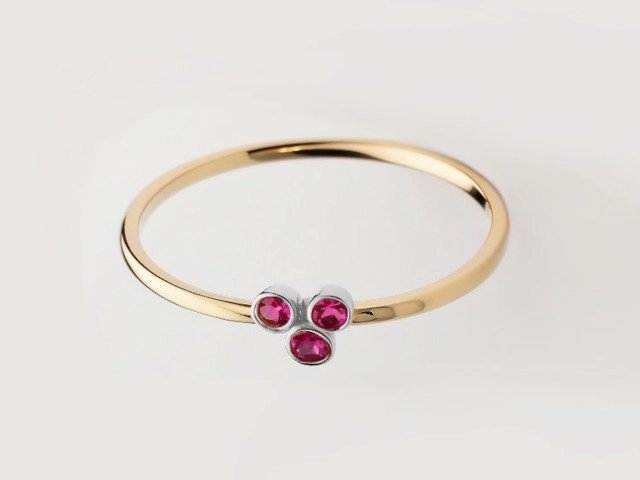  Anillo de oro amarillo con tres piedras preciosas de color rubí, exhibiendo un diseño elegante y contemporáneo.