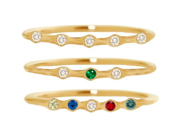 Tres anillos con nudos alineados verticalmente. De arriba abajo un anillo con cinco piedras transparentes el de arriba, el del centro tiene tres piedras dos tranparentes las de los lados y la del medio verde y el tercero el de abajo, lleva cionco pidras de difentes colores.